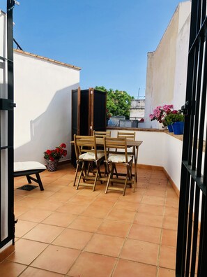 Enjoy a tranquil outdoor space with a table, chairs, and a bench, surrounded by lush greenery and a potted plant.