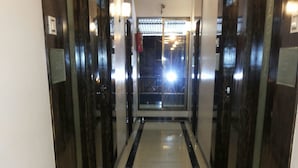 Un pasillo con piso reflectante, puertas de madera oscura y una luz brillante al final.