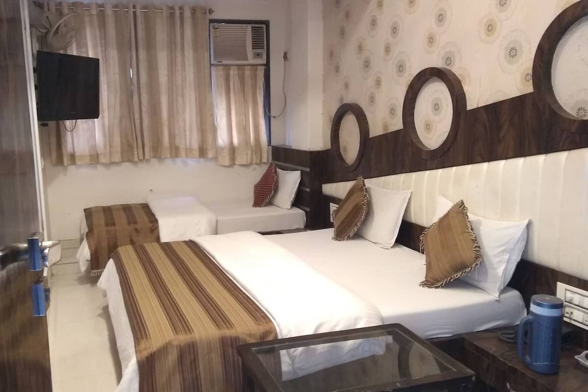 Ein Hotelzimmer mit zwei Betten, einem Flachbildfernseher, einer Klimaanlage und einem Glastisch.