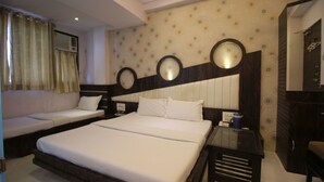 Una habitación de hotel con una cama grande, un sofá, una mesita y un espejo.