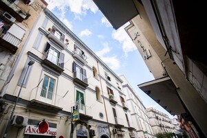 Un edificio de varios pisos con balcones, un letrero que dice 'ANATOLI Viaggi' y un letrero de 'TABACCH'.