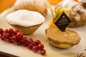 Un plato de postre con un pastel espolvoreado, un donut glaseado y una guarnición de grosellas rojas.