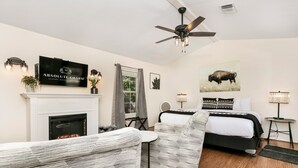 Un dormitorio moderno con chimenea, una cama, un sofá y un ventilador de techo.