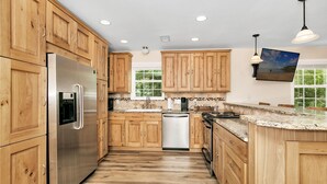 Una cocina con armarios de madera, electrodomésticos de acero inoxidable, lavavajillas y encimera de granito.