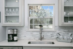 A modern kitchen with a built-in sink, a coffee maker, and a window with a decorative hanging.