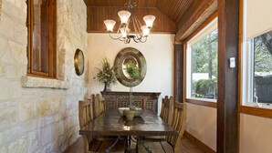 A dining area with a stone wall, wooden table, and chairs.