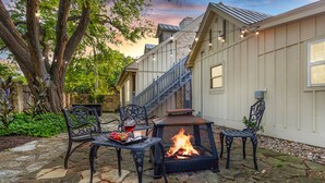 A stone patio with outdoor furniture, a fire pit, and string lights.