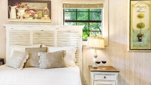 Un dormitorio con cama, mesita de noche, lámpara y una pared decorada con un cuadro.