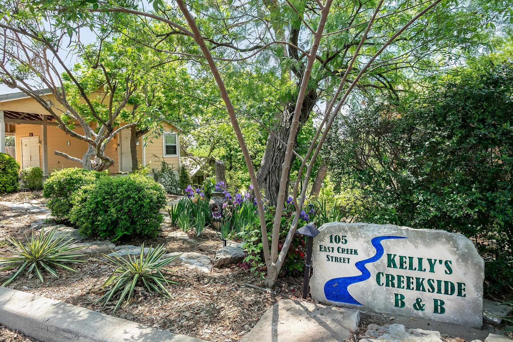 Een stenen bord met 'Kelly's Creekside B & B' en '105 East Creek Street', wat een bed en ontbijt aangeeft.