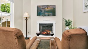 A living room with a fireplace, two brown sofas, a floor lamp, and a painting above the fireplace.