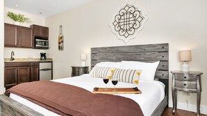A bedroom with a large bed, two bedside tables, a wooden headboard, and a decorative wall piece.