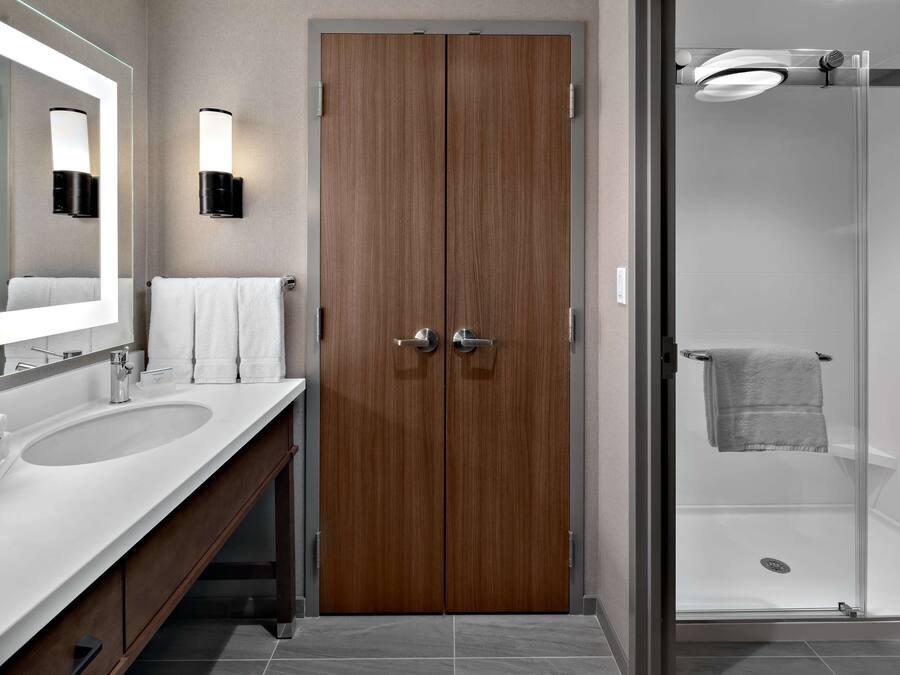 Un baño moderno con lavamanos doble, un espejo grande y ducha con mampara de vidrio.