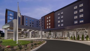 A modern hotel with a central courtyard, multiple floors, and a flagpole. - Homewood Suites by Hilton Boston Woburn (Woburn)