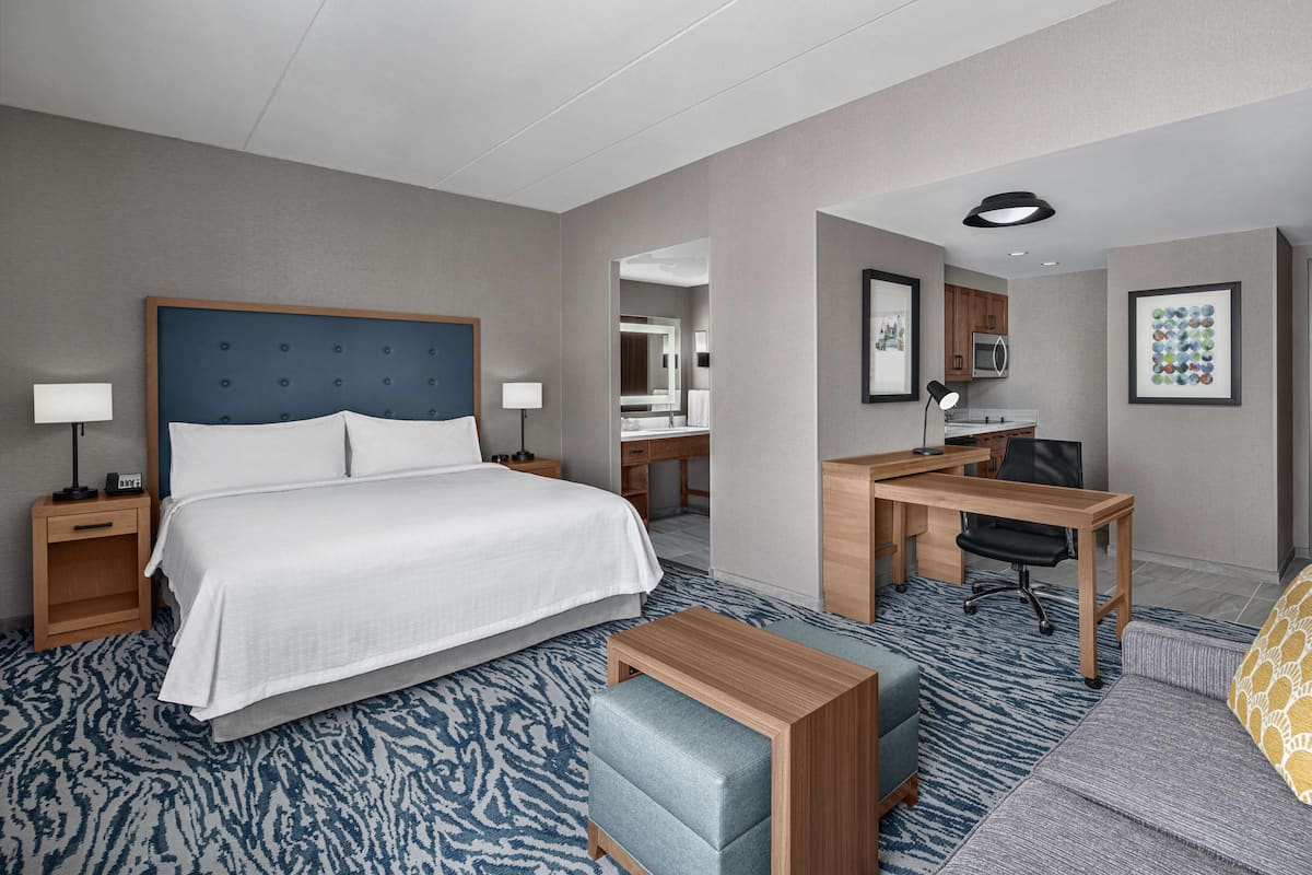 Habitación de hotel con una cama grande, un escritorio, una silla, un sofá y una mesita.