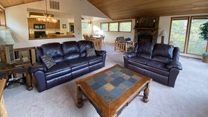 A spacious living room with leather sofas, a wooden coffee table, and a stone fireplace. - Cozy Sunriver Home w/ AC, Fireplace, HotTub, 8 SHARC Passes, Outdoor Heaven (Sunriver)