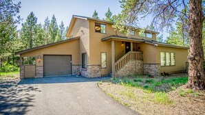 A two-story house with a garage, a front porch, and a stone foundation. - Cozy Sunriver Home w/ AC, Fireplace, HotTub, 8 SHARC Passes, Outdoor Heaven (Sunriver)