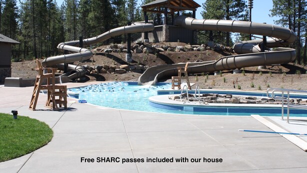 A swimming pool with multiple slides and a wooden deck area. - Cozy Sunriver Home w/ AC, Fireplace, HotTub, 8 SHARC Passes, Outdoor Heaven (Sunriver)
