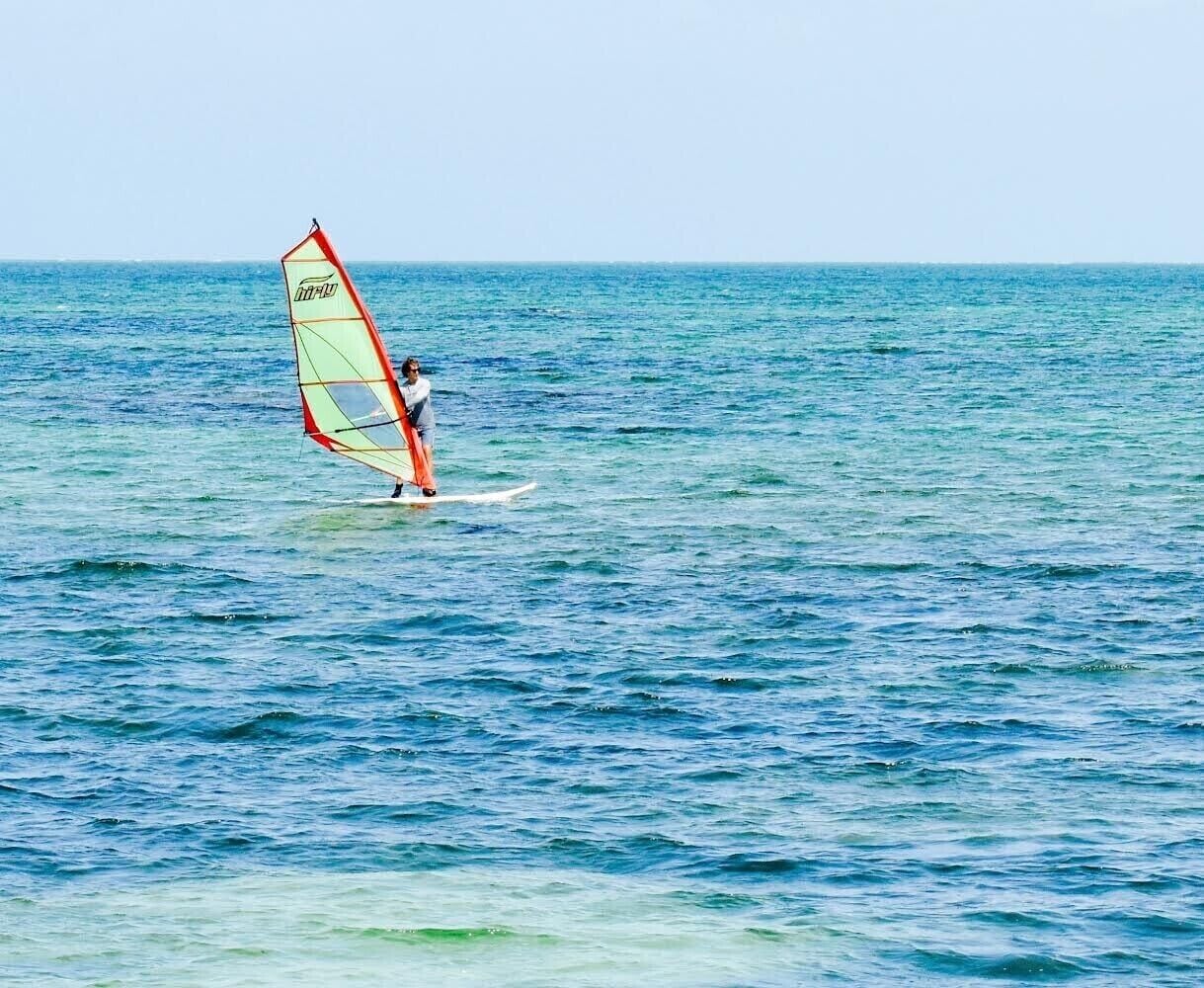 A person windsurfing on a calm sea.