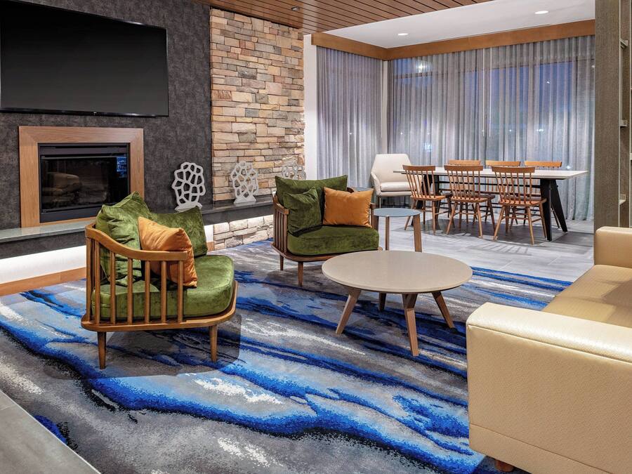 A modern living room with a fireplace, comfortable seating, a dining area, and a large TV.