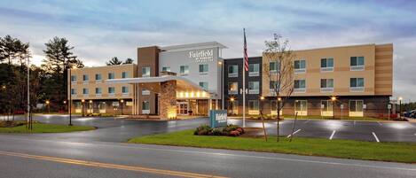 A Fairfield Inn & Suites hotel with a modern design, featuring a large parking lot and a well-lit entrance.