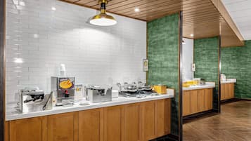 Une cuisine moderne avec des murs recouverts de carreaux blancs, des armoires en bois et des appareils électroménagers en acier inoxydable.