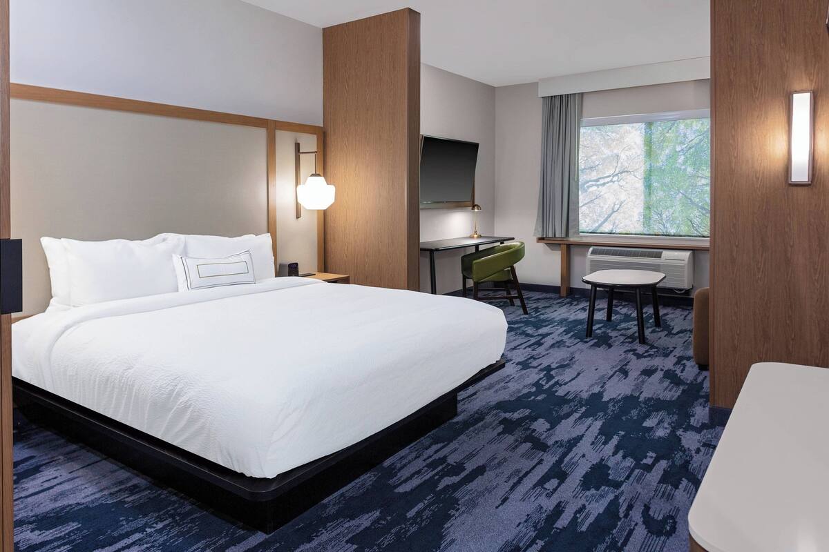 Una habitación de hotel con una cama grande, un escritorio, una silla y una mesita.