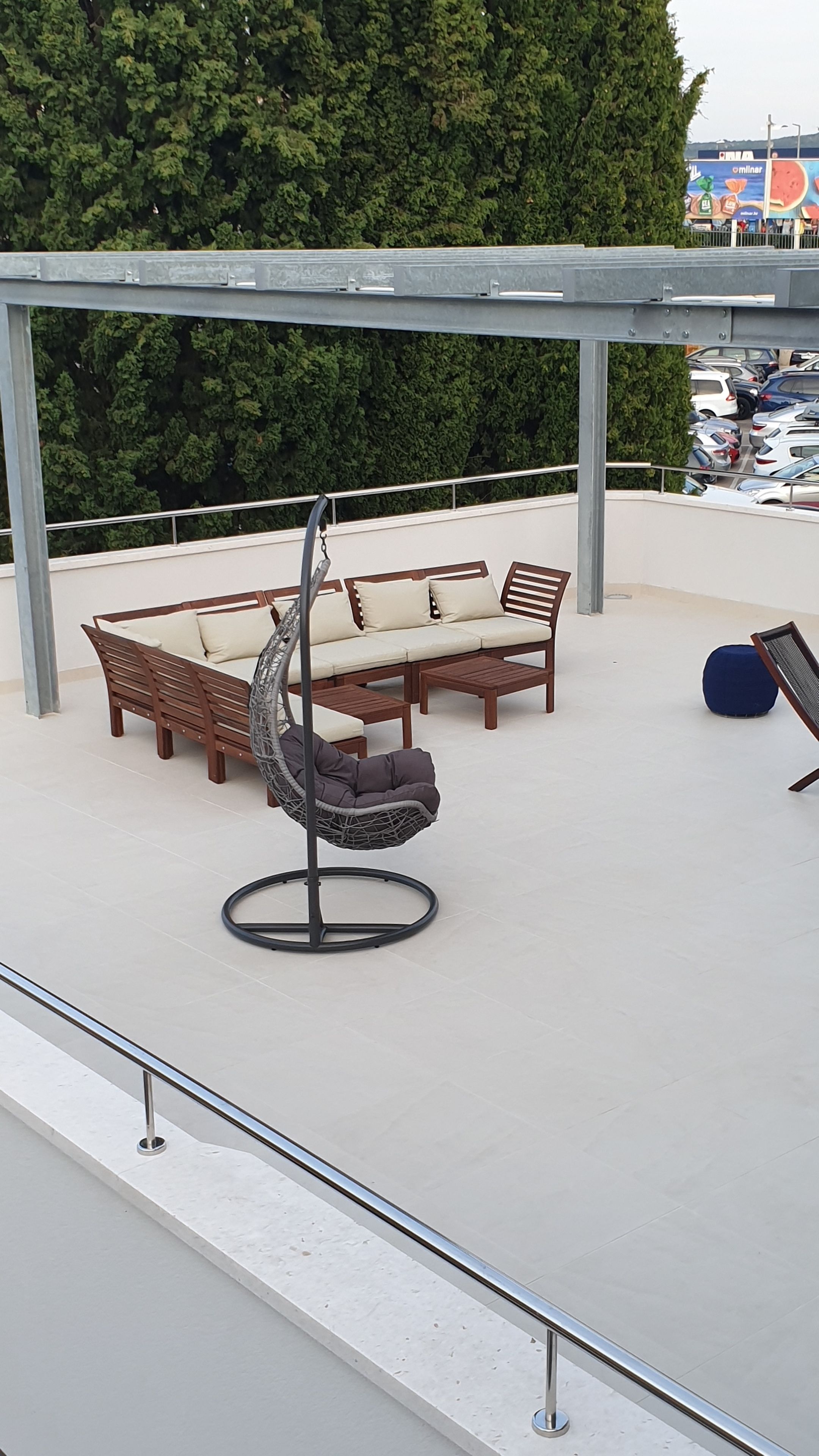 An outdoor seating area with a swing chair, a sofa, and a bench under a pergola.