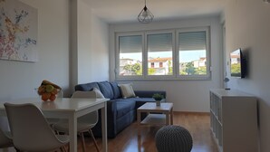 Un salon moderne avec un canapé, une table à manger et un téléviseur fixé au mur.