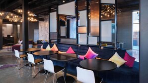 A modern lounge area with seating, tables, and ambient lighting. - Aloft by Marriott Cincinnati West Chester (West Chester)