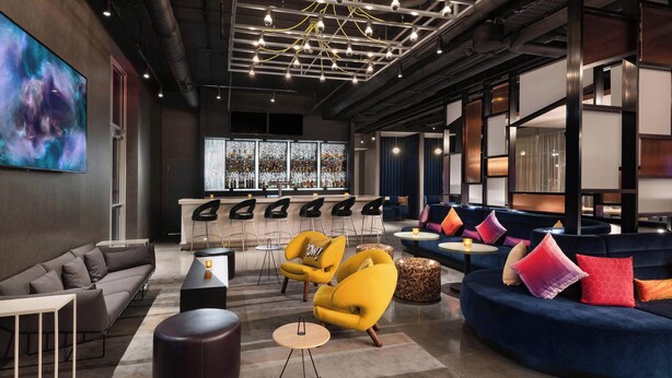 A modern lounge area with sofas, armchairs, and a bar. - Aloft by Marriott Cincinnati West Chester (West Chester)