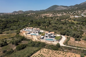 A modern villa with a swimming pool, surrounded by lush greenery and hills. - Kefalonia Stone Villas - Villa Petros Kefalonica (Trapezaki, Kefalonia)