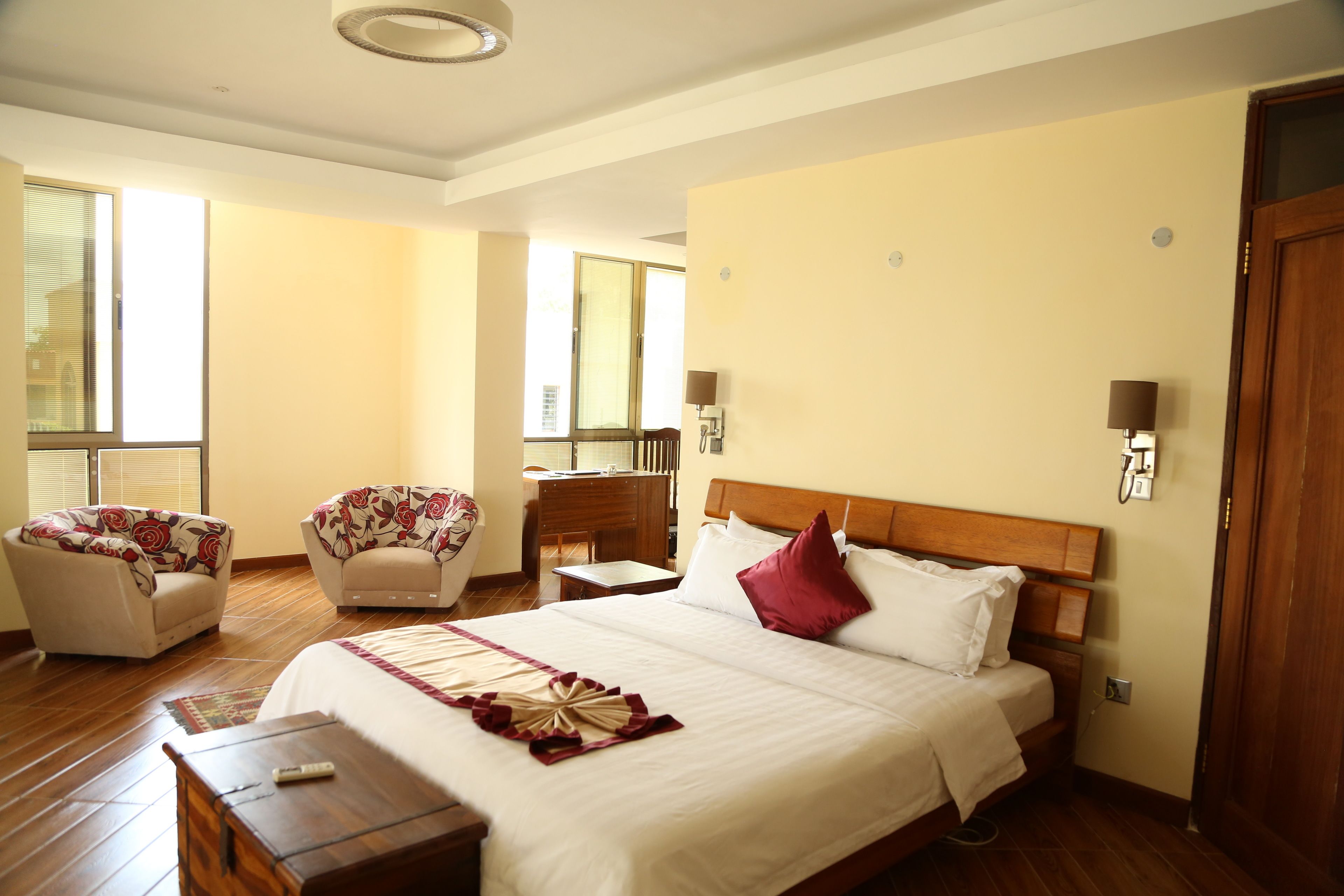 A hotel room with a large bed, two armchairs, a desk, and a window.