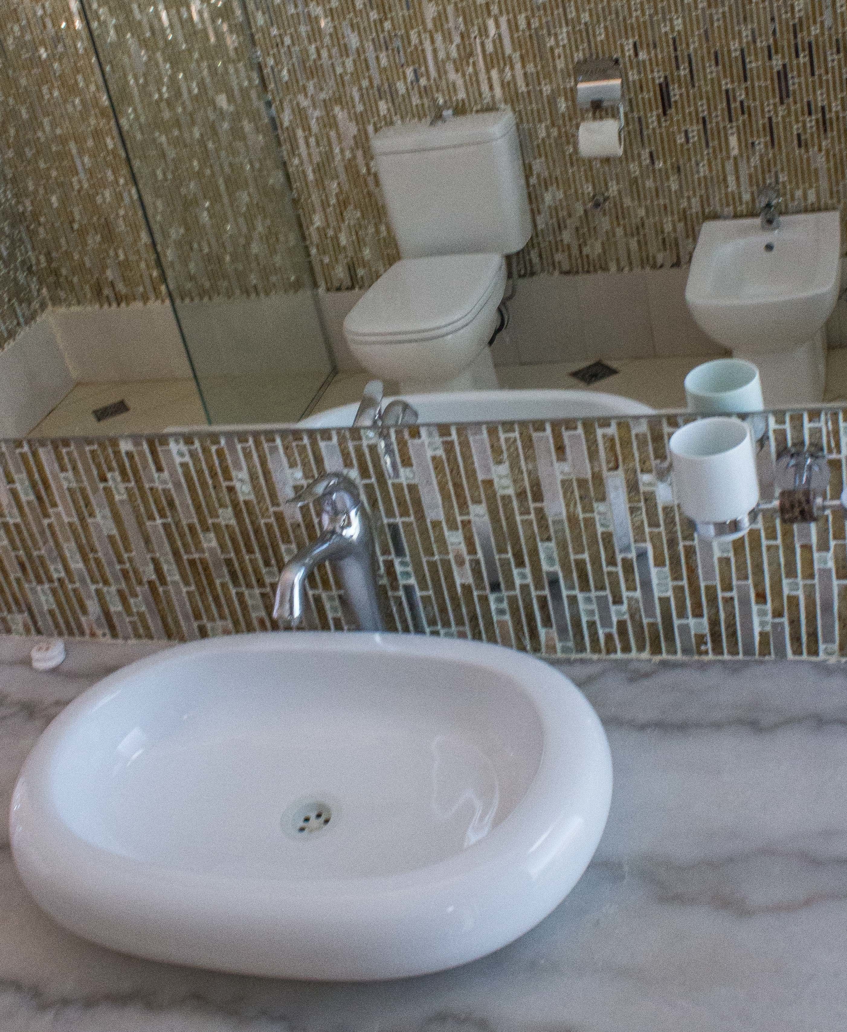 A bathroom with a white sink, a mirror, and a toilet.