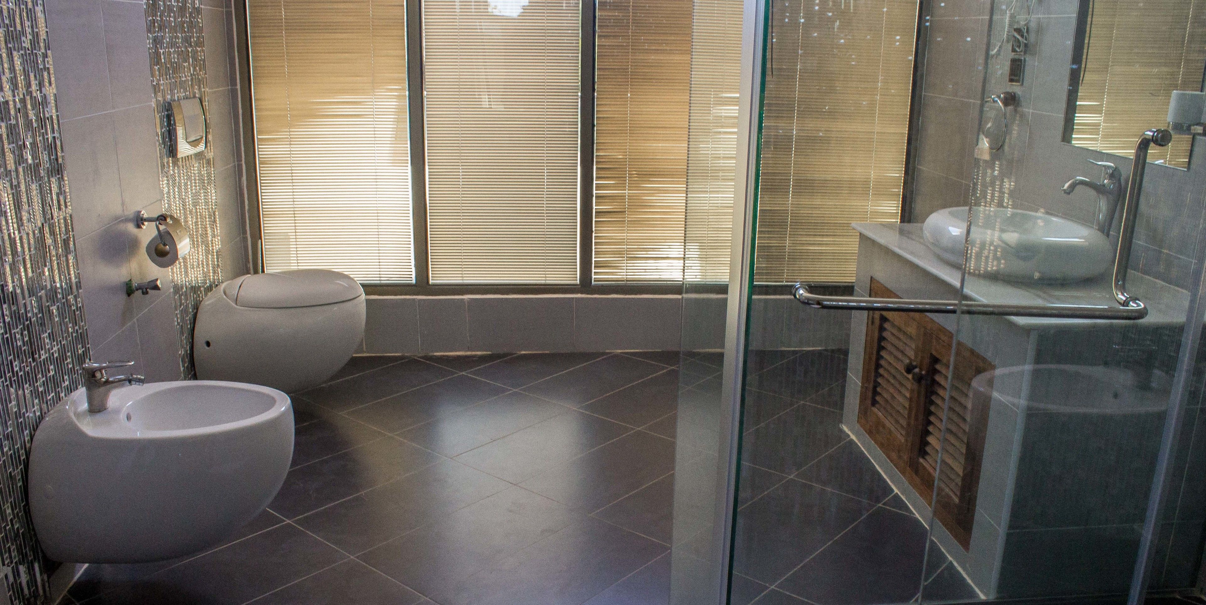 A modern bathroom with a glass shower enclosure, a toilet, and a sink.