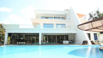 Alberca al aire libre, sombrillas en la alberca y camastros