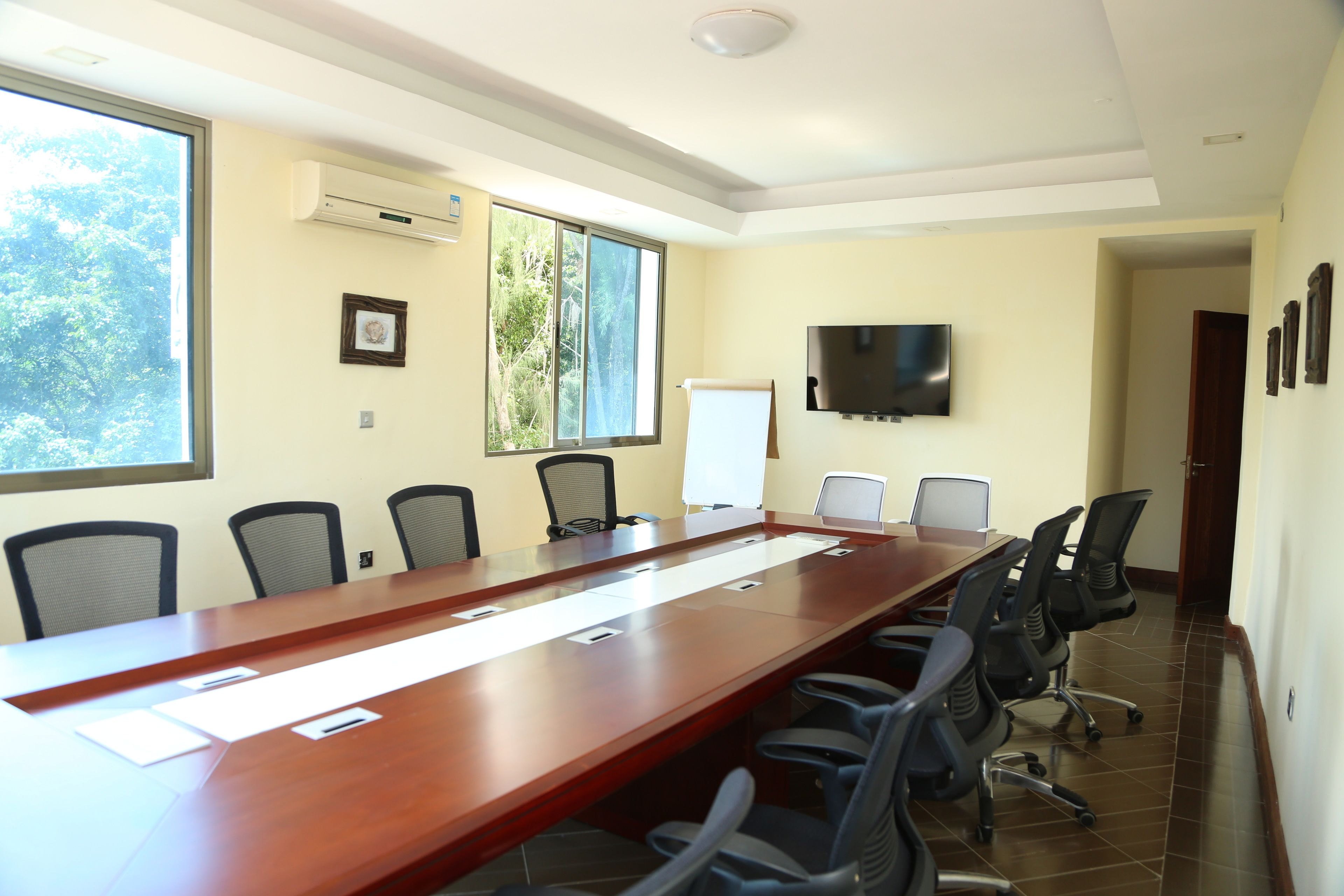 A conference room with a long table, chairs, a whiteboard, and a TV on the wall.