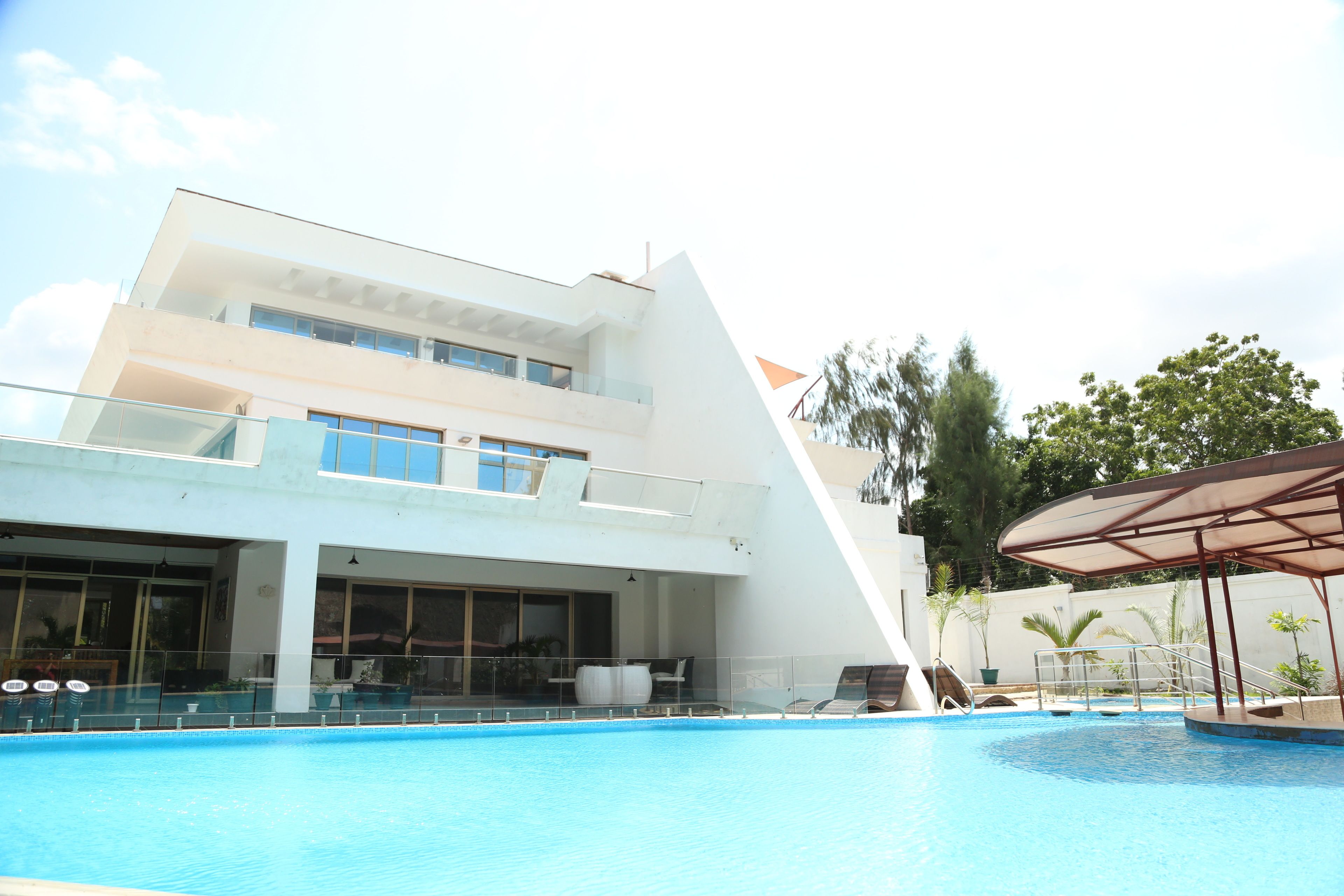 Un bâtiment moderne doté d’une piscine, d’un espace salon couvert et d’un escalier menant à un niveau supérieur.