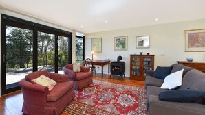A living room with a red sofa, a grey sofa, a patterned rug, a wooden cabinet, and a fireplace. - Narrow Neck Views - Spacious Mountains Home with Stunning Views! (Katoomba)