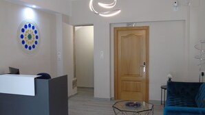 A modern living room with a reception desk, a blue sofa, a glass coffee table, and a wooden door. - Casa San Nicolás (Portomarin)