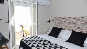 A hotel room with a bed, a desk, a chair, and a view of the outside. - Casa San Nicolás (Portomarin)