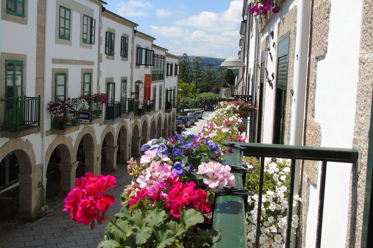 A narrow street with buildings on either side, each adorned with flower boxes.