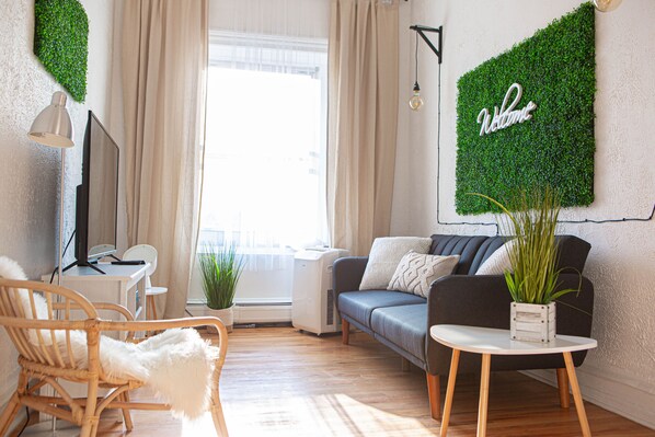 Relax in this serene living space with a comfortable sofa, wooden chair, and potted plant.