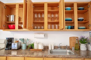 Kitchen features a stainless steel sink, granite countertop, and ample storage space with cabinets and shelves.