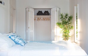 Cozy retreat with a neatly made bed, wardrobe, and a touch of greenery.