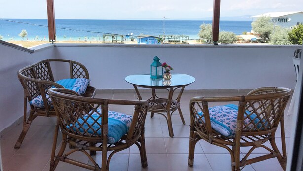 A balcony with wicker furniture, a glass table, and a view of the sea. - Kumsal Suit (Marmara)