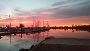 Een jachthaven met aangemeerde boten, stilstaand water en een zonsondergang.