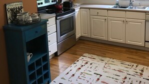 A kitchen with white cabinets, a stove, and a microwave. There is a window with a view of trees outside. - Walk to Carrollton Square!  Entire Home Upstairs For Rent.  (Carrollton)