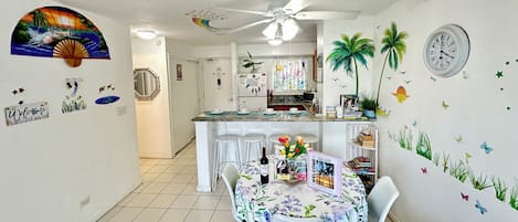 Una cocina con comedor, paredes blancas y un ventilador de techo.