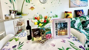 Une pièce décorée sur le thème des tropiques, avec des autocollants représentant des palmiers sur les murs, une horloge, une pancarte de bienvenue, une bouteille et un guide touristique.