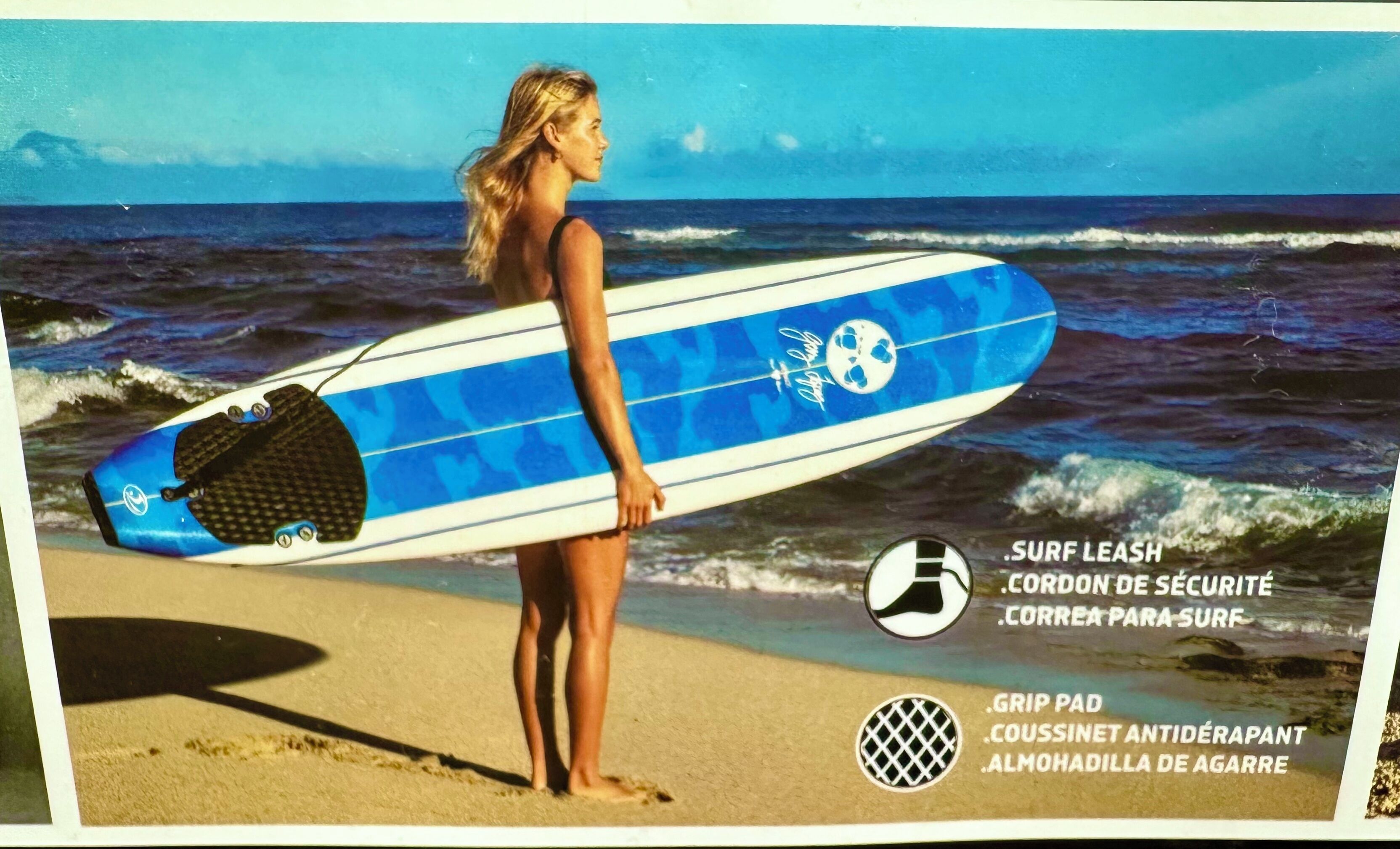 A person holding a surfboard on a beach with waves in the background.